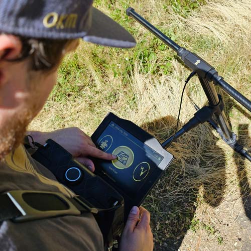 Person using a detector with app in a field